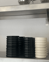 Grip Cups in black and white on a metall shelf.