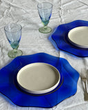 This blue colored glass plate in a flower-like curvy shape is a perfect dinner plate. 
