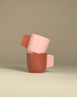 Two ceramic espresso cups. One in a powdery pink with a terracotta colored handle and vise versa.